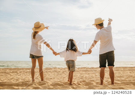 Happy Asian parents with their daughters enjoying playful at beach. Little girls with their mother and father holding hand of child walking on sand beach. Positive family outdoor activity Happy Asian parents with their daughters enjoying playful at beach. Little girls with their mother and father holding hand of child walking on sand beach. Positive family outdoor activity 124240528