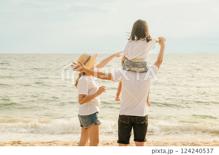 Happy family in holiday. Father, Mother and kids having fun together shoulder ride on summer beach, Parents carrying children on neck at beach, family is enjoying their summer time 124240537