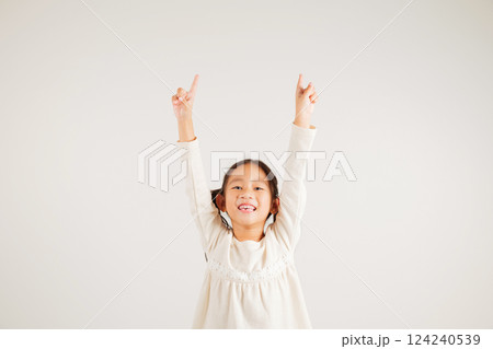 Asian happy portrait cute young kid girl makes gesture fingers point upwards above presenting product something, studio shot isolated on white background, kindergarten children woman smile Asian happy portrait cute young kid girl makes gesture fingers point upwards above presenting product something, studio shot isolated on white background, kindergarten children woman smile 124240539