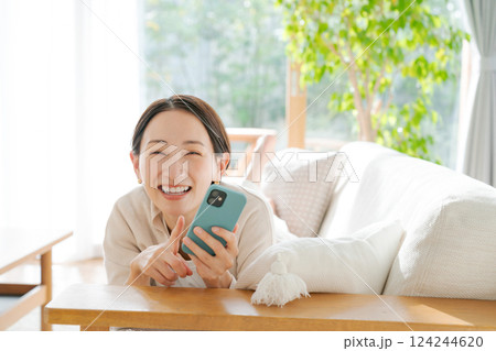 ソファに寝転んでスマホを見る女性 ソファに寝転んでスマホを見る女性 124244620