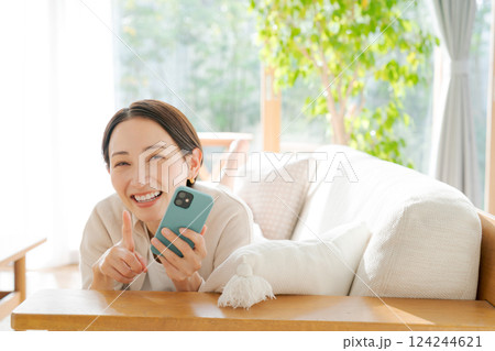 ソファに寝転んでスマホを見る女性 124244621