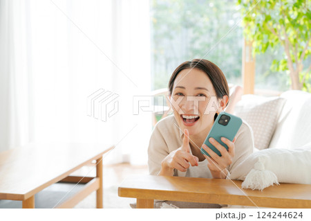 ソファに寝転んでスマホを見る女性 124244624