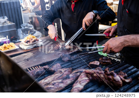 Some excellent pieces of Argentinian beef on a charcoal grill being prepared at open kitchen street food festival in Ljubljana, Slovenia 124248975