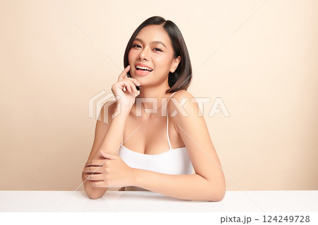 A beautiful young Asian woman with clean, fresh skin against a beige background. Skincare, facial treatment, cosmetology, beauty, and spa. An elegant portrait of an Asian woman. 124249728