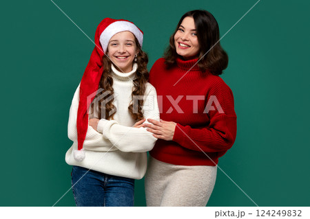 Mum, teenage daughter wearing red and white sweaters, arms linked 124249832