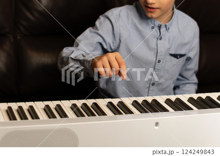 Boy pointing at key on the keyboard while playing. Boy pointing at key on the keyboard while playing. 124249843