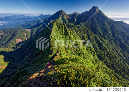 八ヶ岳連峰・権現岳の岩稜を行く登山者と赤岳・阿弥陀岳の眺め 124250946