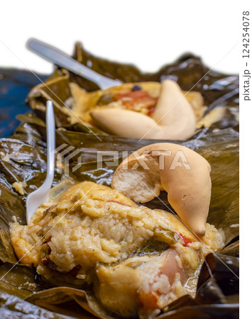 Close up of two Nacatamales in banana leaf served on table. Two Nacatamales served in a banana leaf on a wooden table. Nacatamales with bread served at the table, Traditional Hallaca served 124254078