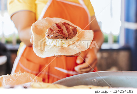 Preparation of the dough for traditional Nicaraguan pupusas, Elaboration of traditional mixed pupusas, Hands of a vendor showing traditional raw pupusa. 124254192