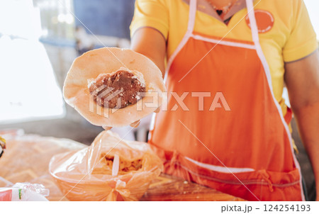 Hand of a vendor showing traditional raw pupusa. Elaboration of traditional pupusas, Preparation of the dough for traditional Nicaraguan pupusas 124254193