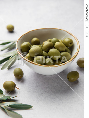 Fresh green olives in a bowl with olive branches on marble table 124254257