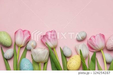 Easter eggs and tulips creating a festive spring border on pink background 124254287