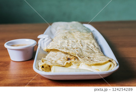 Close up of a Nicaraguan quesillo served on wooden table. Top view of Nicaraguan Quesillo on a plate served on wooden table. Delicious traditional Nicaraguan quesillo served on wooden table Close up of a Nicaraguan quesillo served on wooden table. Top view of Nicaraguan Quesillo on a plate served on wooden table. Delicious traditional Nicaraguan quesillo served on wooden table 124254289