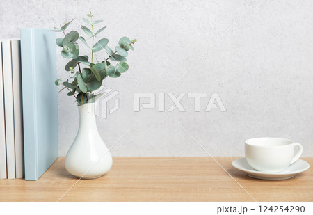 Eucalyptus branches, books, and coffee cup creating a cozy atmosphere on wooden desk Eucalyptus branches, books, and coffee cup creating a cozy atmosphere on wooden desk 124254290