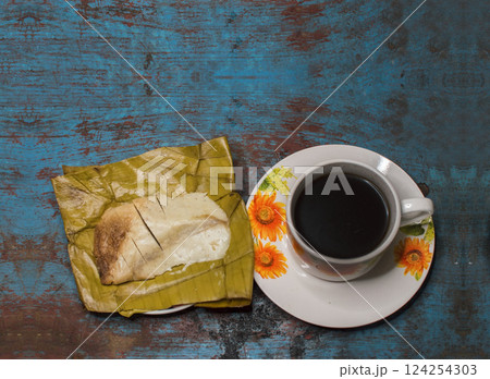 Traditional Stuffed Pisque Tamal with cup of coffee served on wooden table, Central American typical food Stuffed Tamal Pisque, Stuffed tamale with cup of coffee served on wooden table 124254303