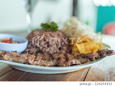 Close up of roast beef with gallo pinto and pico de gallo, Nicaraguan food served on wooden table, Plate with roast beef and rice served on wooden table 124254352