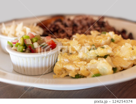 Gallopinto breakfast served on table, gallopinto with fried eggs with pico de gallo on wooden table. Traditional gallopinto dish with fried eggs and pico de gallo served on the table 124254374