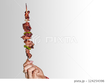 A hand holding a roast beef skewer, Hand holding roast beef skewer on white background 124254396