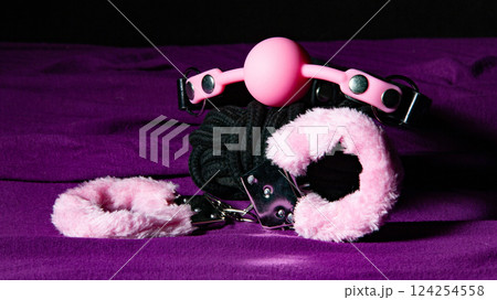 Bdsm outfit. Bondage handcuffs and Gag ball on the purple bedsheet. Adult sex games. Kinky lifestyle. 124254558