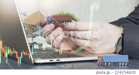 businessman holding a miniature truck over a laptop with stock market graphs, symbolizing logistics, supply chain investment, and e-commerce growth. businessman holding a miniature truck over a laptop with stock market graphs, symbolizing logistics, supply chain investment, and e-commerce growth. 124254620