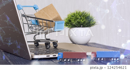 Mini shopping cart with a package on a laptop keyboard, symbolizing e-commerce, online shopping, and digital retail with logistics. 124254621
