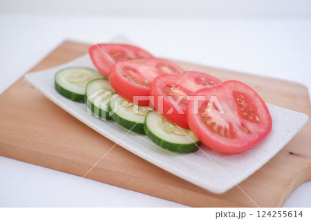Cucumber and tomato slices on a plate on a white background Cucumber and tomato slices on a plate on a white background 124255614