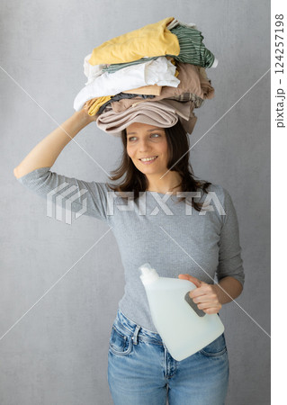 washing clothes, woman holds stack clothes on her head conditioner for laundry after dry cleaning. washing clothes, woman holds stack clothes on her head conditioner for laundry after dry cleaning. 124257198