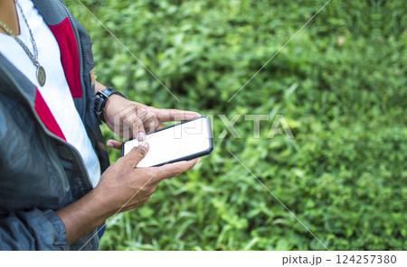 Close up of a man with cell phone in hand, close up of hands with cell phone with white screen, young guy with cell phone in hand with copy space Close up of a man with cell phone in hand, close up of hands with cell phone with white screen, young guy with cell phone in hand with copy space 124257380
