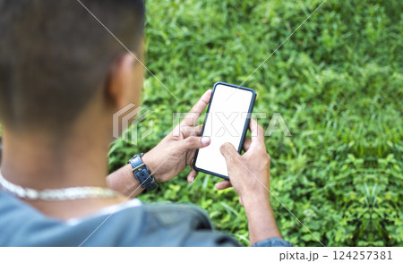 Close up of a man with cell phone in hand, close up of hands with cell phone with white screen, young guy with cell phone in hand with copy space Close up of a man with cell phone in hand, close up of hands with cell phone with white screen, young guy with cell phone in hand with copy space 124257381