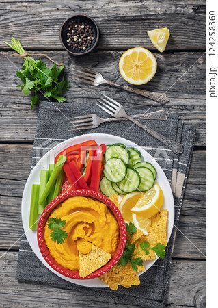 creamy roast carrot hummus in red bowl 124258360