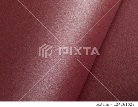 Elegant dark burgundy paper texture with a shimmering, glittering finish and subtly rolled edges. 124261028