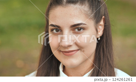 Teenage girl with freckles beaming, sunlight highlighting cheerful expression in lively outdoor environment Teenage girl with freckles beaming, sunlight highlighting cheerful expression in lively outdoor environment 124261261