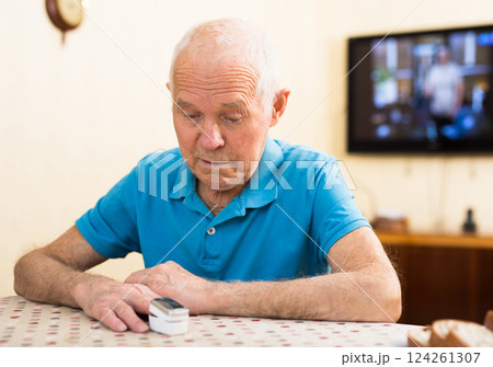 Worried elderly man measuring himself oxygen saturation at home 124261307