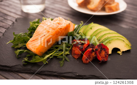 Baked sea trout fillet with fresh vegetables and herbs on black board 124261308