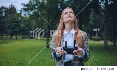 Businesswoman piloting a drone in a park, enjoying modern technology and outdoor activities 124261336