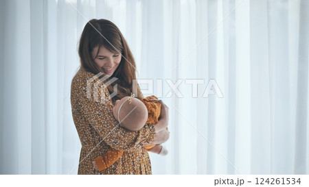 Soft morning light illuminating mother gently hugging newborn baby, sharing intimate bonding moment near window at home Soft morning light illuminating mother gently hugging newborn baby, sharing intimate bonding moment near window at home 124261534