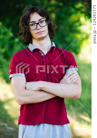 Confident young man standing outdoors, crossing arms with relaxed posture, embodying casual style and self assurance Confident young man standing outdoors, crossing arms with relaxed posture, embodying casual style and self assurance 124261575