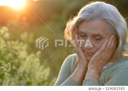 Senior woman feeling peaceful outdoors in sunset light 124261583