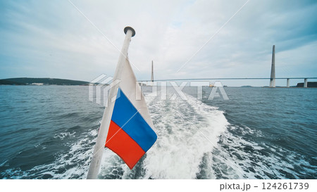 Sailing boat traversing waters near russky bridge, russian flag fluttering against cloudy skyline, capturing maritime panorama in vladivostok Sailing boat traversing waters near russky bridge, russian flag fluttering against cloudy skyline, capturing maritime panorama in vladivostok 124261739