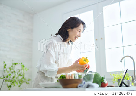 タブレットでレシピを見ながら料理をするミドル女性 タブレットでレシピを見ながら料理をするミドル女性 124262475