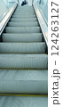 Escalator steps are seen moving upward in a modern public area. The environment is bright and clean, indicating a busy atmosphere typical for daytime visits. 124263127