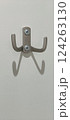 A wall hook designed with a sleek finish is mounted on a white wall. The hooks create interesting shadows, adding a touch of creativity to the minimalist decor. 124263130
