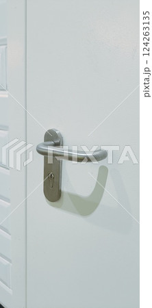 A white door stands against a backdrop of glossy white tiles and black lower wall tiles. The door features a contemporary handle, enhancing the minimalistic decor of the area 124263135