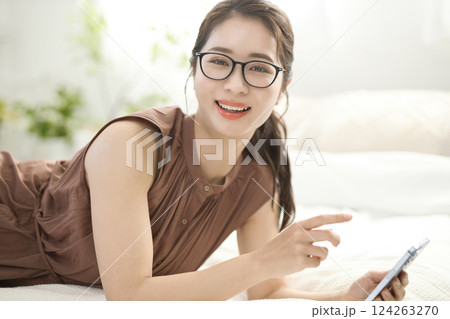 ベッドでくつろいでスマホを見る若い女性 ベッドでくつろいでスマホを見る若い女性 124263270