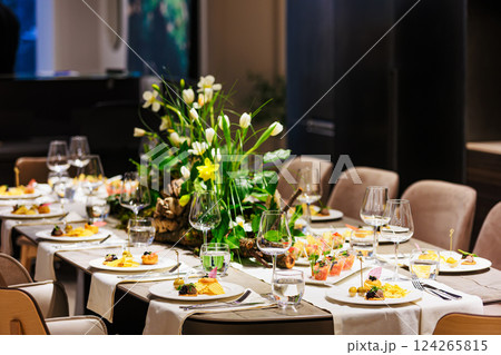Elegant floral centerpiece with white tulips and lush greenery on a luxurious dining table 124265815