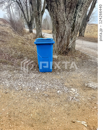 Blue Garbage Bin on Rural Gravel Path, Trees in Background, Outdoor Waste Management, Natural Setting. High quality photo Blue Garbage Bin on Rural Gravel Path, Trees in Background, Outdoor Waste Management, Natural Setting. High quality photo 124266440