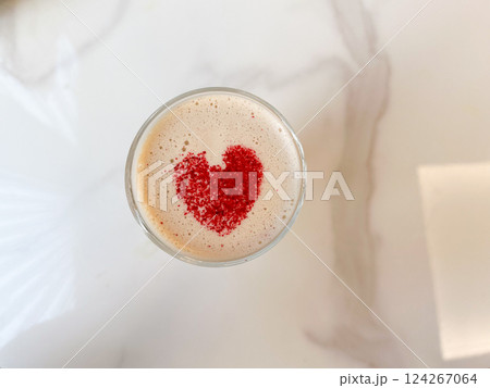 Glass cup of fresh hot aromatic cappuccino with latte art in shape of heart served on table. Glass cup of fresh hot aromatic cappuccino with latte art in shape of heart served on table. 124267064