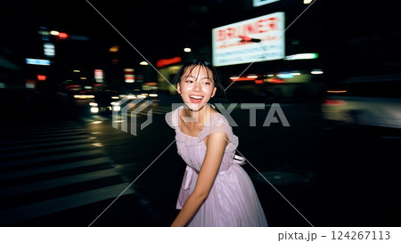 A flash-lit shot of a young woman wearing an elegant dress, in the middle of a busy city at night. Youth and happiness concept 124267113