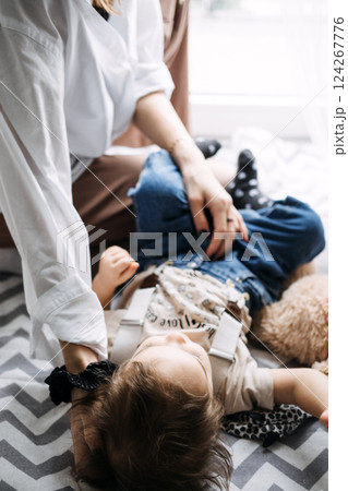 Mother and child on patterned floor, gentle interaction. Parenting moments, child care, cozy indoor setting, maternal bond, early childhood development. Mother and child on patterned floor, gentle interaction. Parenting moments, child care, cozy indoor setting, maternal bond, early childhood development. 124267776