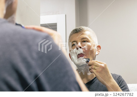 Reflection in the mirror of the man shaving Reflection in the mirror of the man shaving 124267782